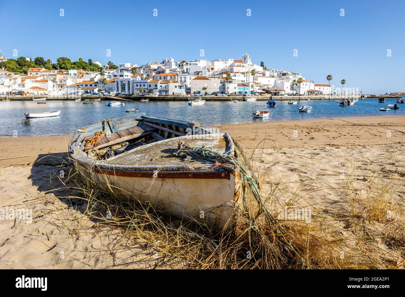 Paysage urbain de Ferragudo avec architecture blanchie à la chaux et bateaux en premier plan, Algarve, Portugal Banque D'Images