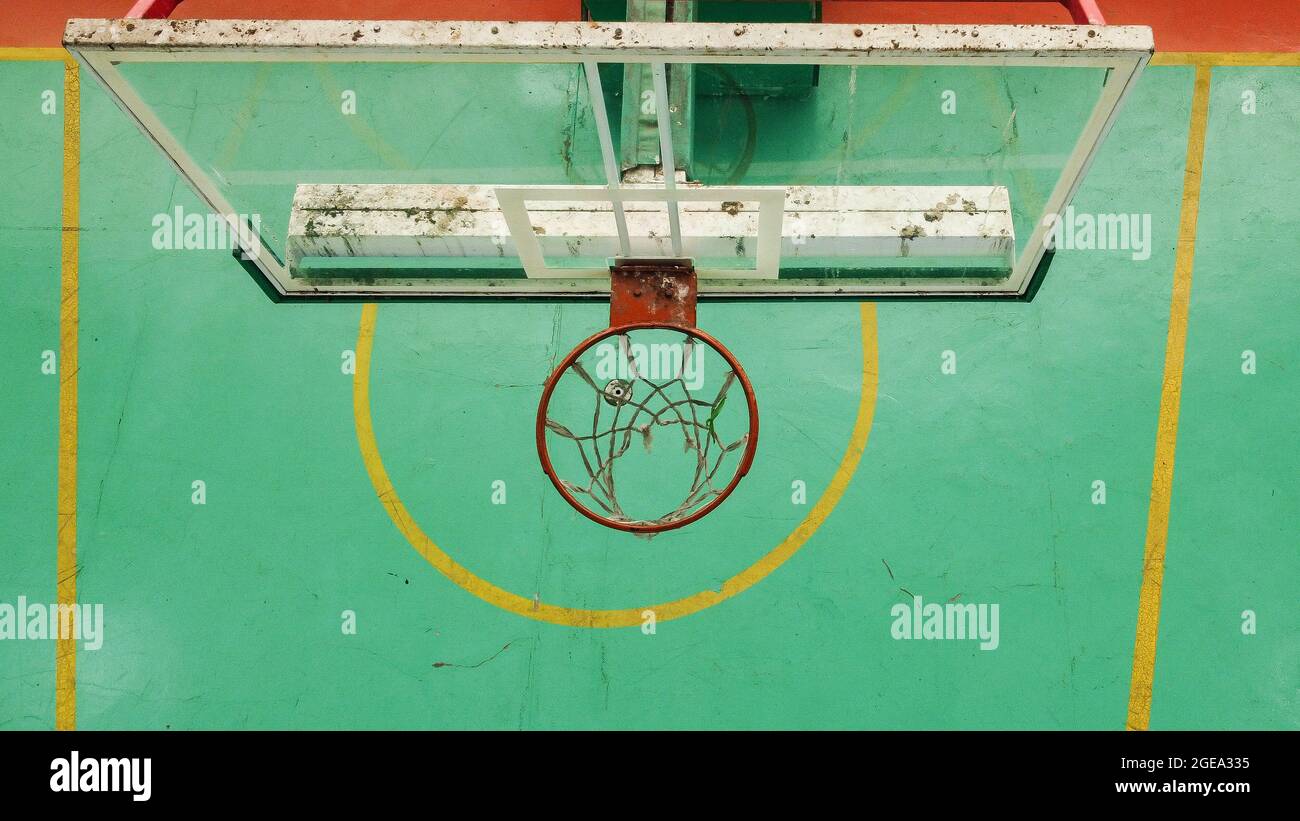 Un panier de basket-ball rouillé et tacheté de la météo vu d'en haut, le  terrain vert en arrière-plan et les marques sont sales et décolorées Photo  Stock - Alamy