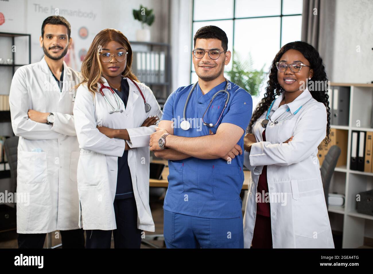 Portrait d'une équipe médicale multiethnique confiante, debout avec les bras croisés à l'hôpital. Des étudiants en médecine afro-américains, indiens et arabes posaient à la caméra dans une salle de conférence moderne Banque D'Images