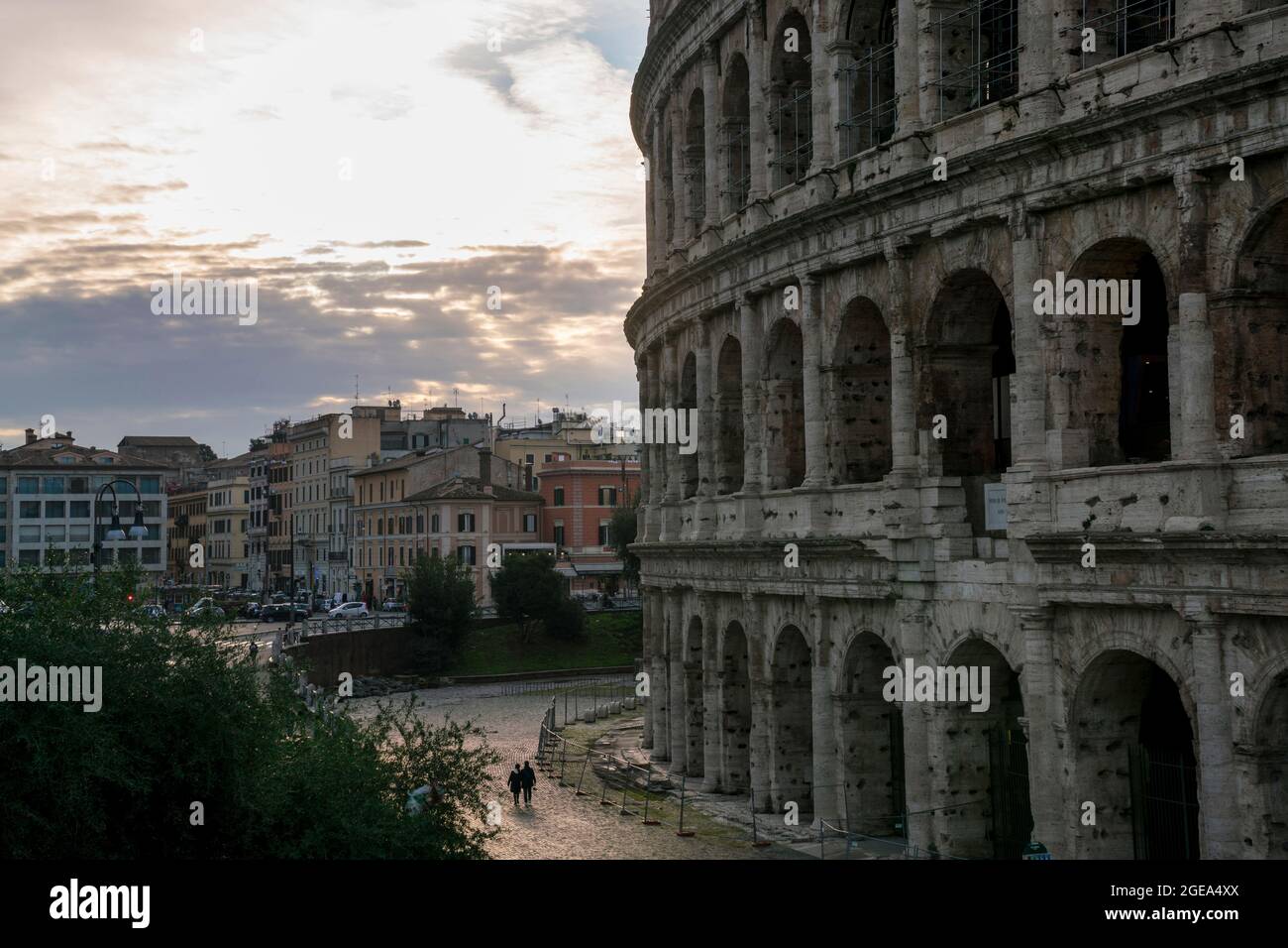 Un couple marche sous l'imposante structure du Colisée à Rome. Banque D'Images