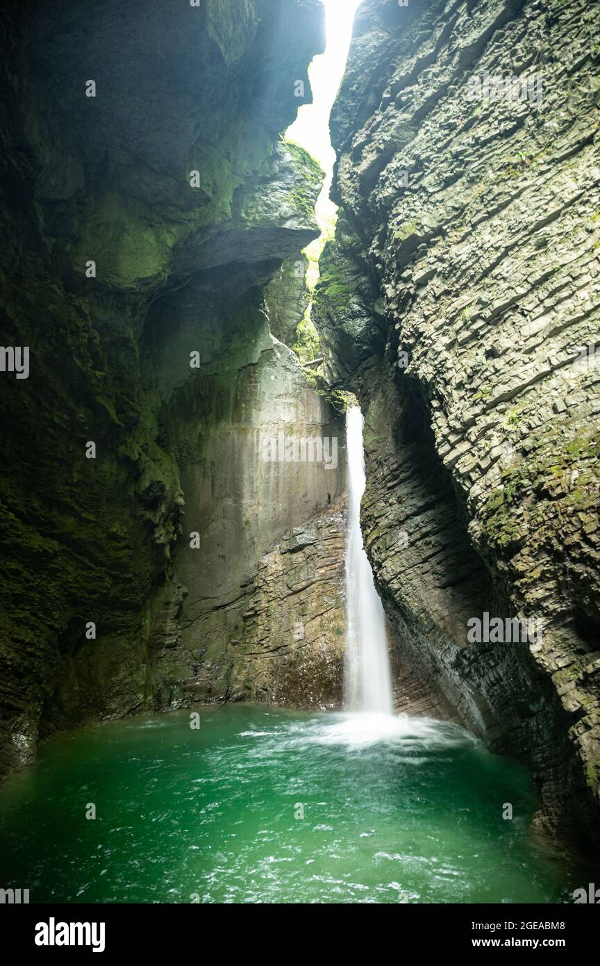 Cascade cristalline dans une grotte calcaire inondée de lumière du soleil et d'eau bleue Banque D'Images