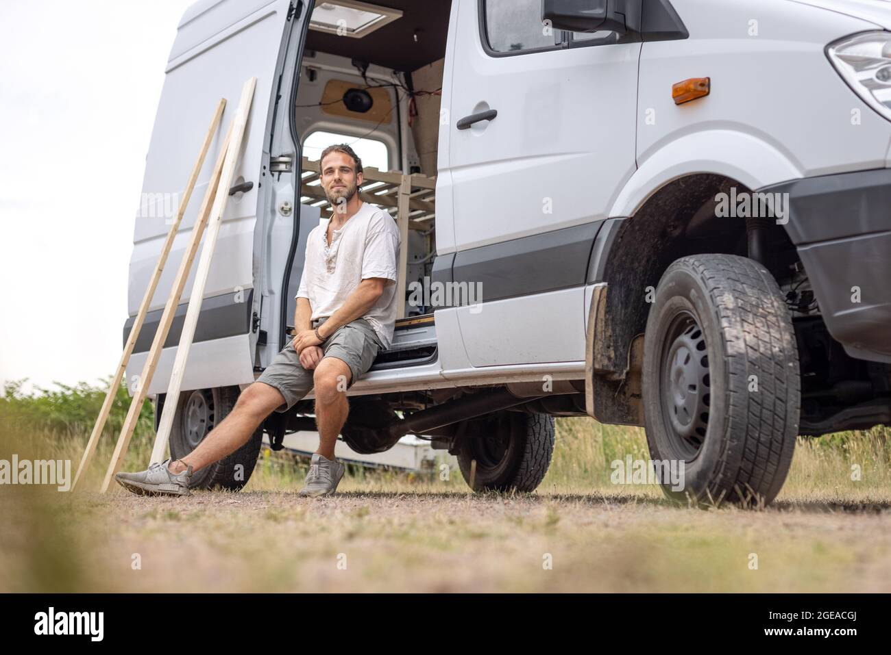 Homme assis dans la porte de sa camionnette de camping Banque D'Images
