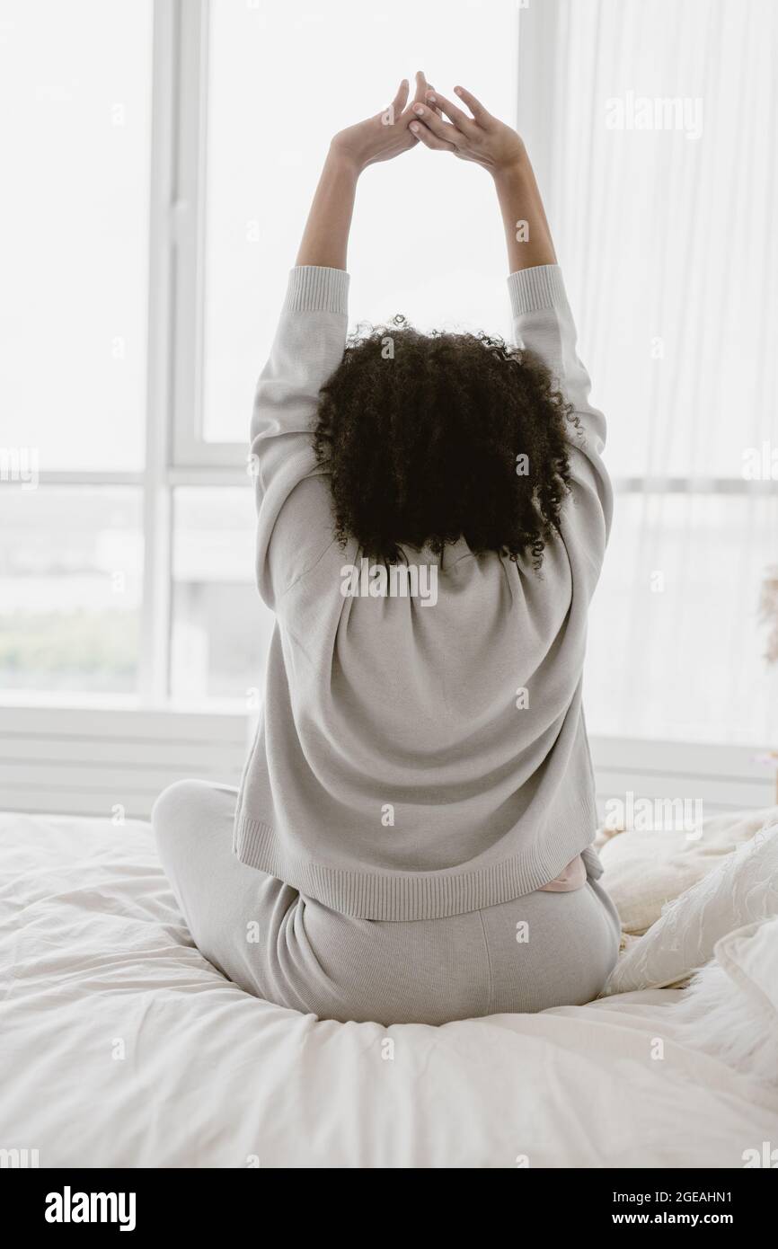 Femme afro-américaine s'étirant au lit après le réveil. Banque D'Images