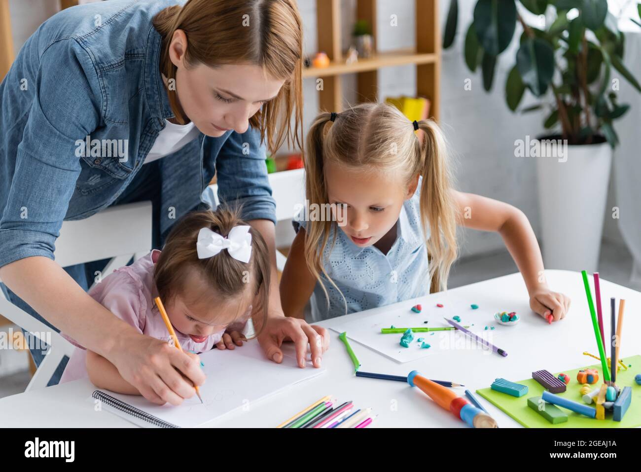 enseignant aidant l'enfant handicapé avec le syndrome de down dessin dans la maternelle privée Banque D'Images