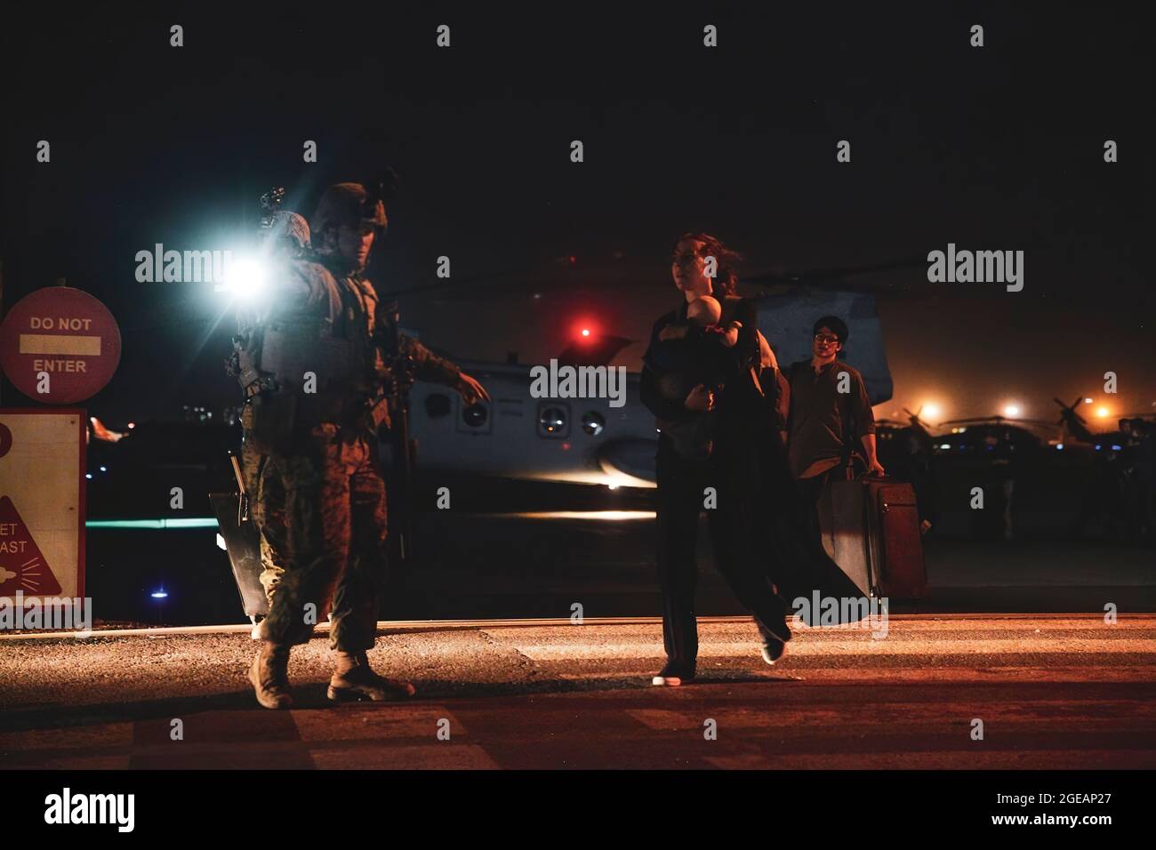 Un Marine affecté à la 24e unité expéditionnaire maritime (UMM) escorte un employé du département d'État qui sera traité pour évacuation à l'aéroport international Hamid Karzaï, Kaboul, Afghanistan, août 15. Les soldats américains et les Marines aident le Département d'État à faire un retrait ordonné du personnel désigné en Afghanistan. (É.-U. Photo du corps marin par Sgt. Isaiah Campbell) Banque D'Images