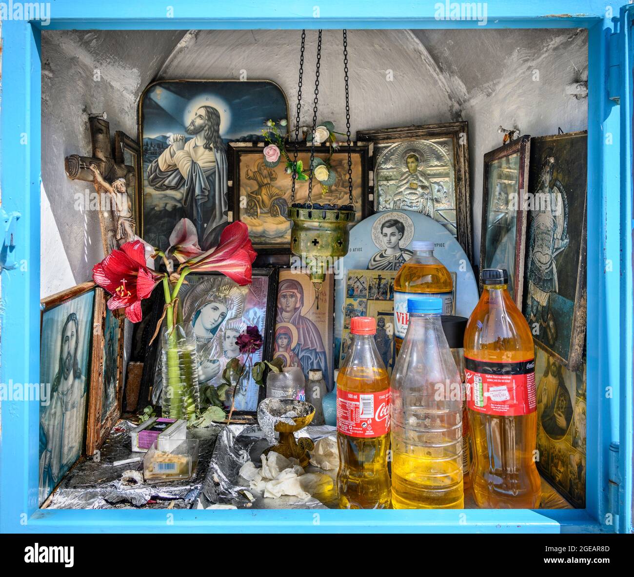 L'intérieur d'un sanctuaire grec orthodoxe en bord de route présentant des icônes religieuses, des bouteilles d'huile sainte et des brûleurs à encens. Arcadia, Péloponnèse, Grèce Banque D'Images