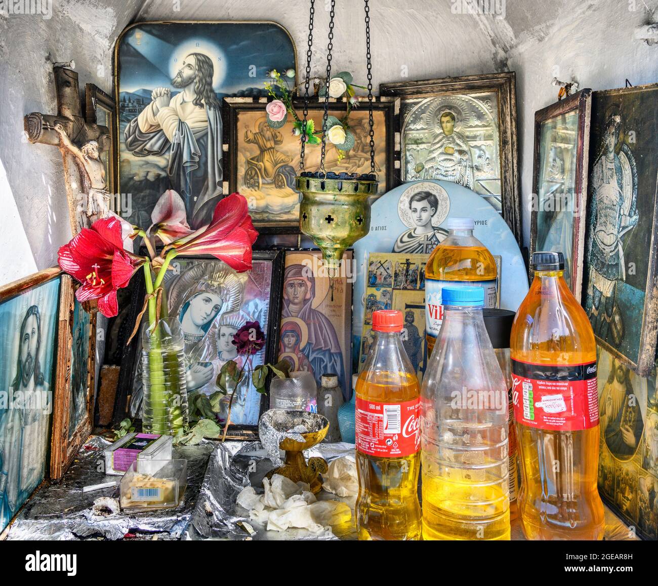 L'intérieur d'un sanctuaire grec orthodoxe en bord de route présentant des icônes religieuses, des bouteilles d'huile sainte et des brûleurs à encens. Arcadia, Péloponnèse, Grèce Banque D'Images