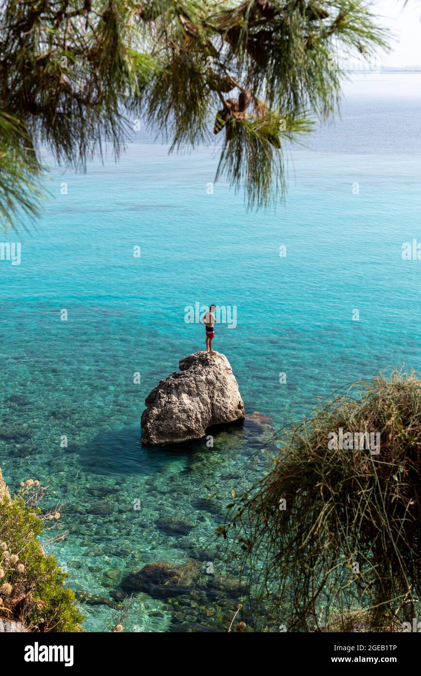 L'île de Lefkada. Grèce- 08.05.2021: Un touriste debout sur un rocher prêt à plonger dans la belle mer turquoise. Banque D'Images