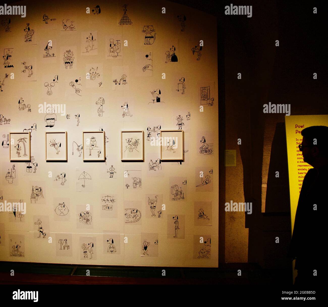 Exposition d'art de cacahuètes : Snoopy & Charlie Brown avec un homme silhoueté qui observe l'œuvre d'art. Banque D'Images