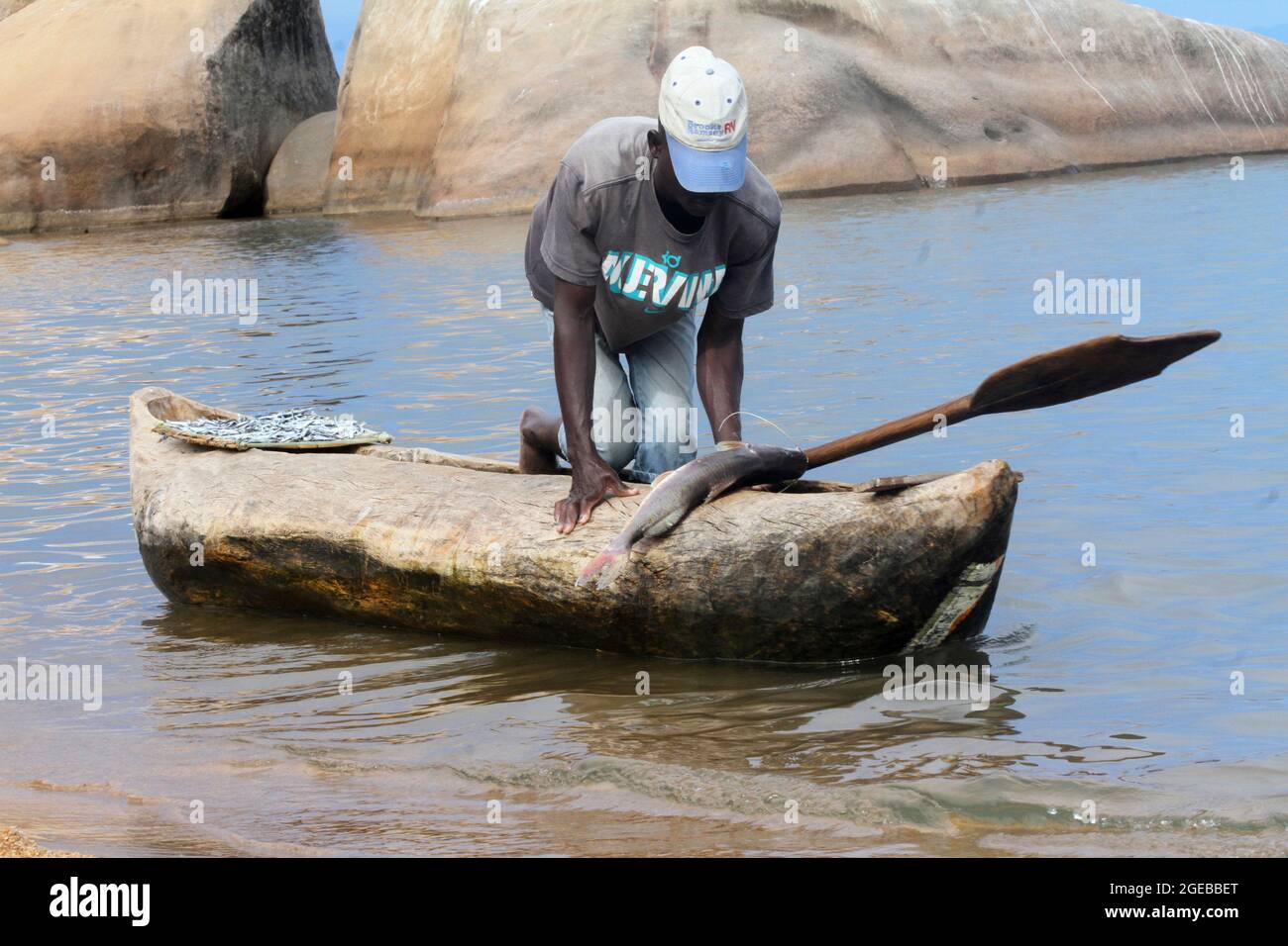 Un pêcheur est vu ancrage en amenant ses prises du lac Malawi à la baie de Senga, pour vendre aux fêtards de plage. Salima, Malawi. Banque D'Images