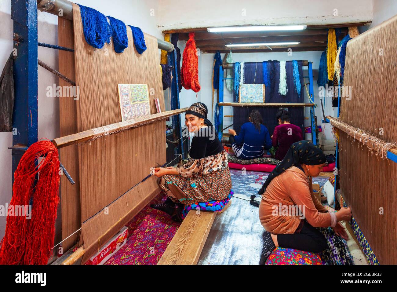 Khiva, Ouzbékistan - 15 avril 2021 : des femmes locales serpentant un tapis artisanal ouzbek traditionnel dans la ville de Khiva, en Ouzbékistan Banque D'Images