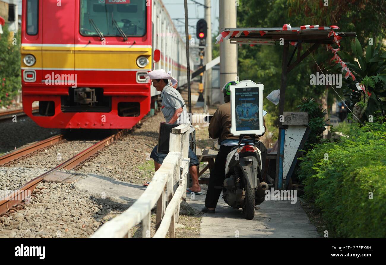 Jakarta, Indonésie-16 août 2021 : motocycliste attendant que le train passe avant de traverser les voies ferrées Banque D'Images