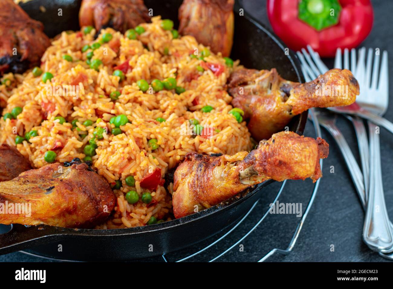 Pilons de poulet rôtis au riz djuvec serbe servis dans une casserole en fonte sur fond de table sombre Banque D'Images