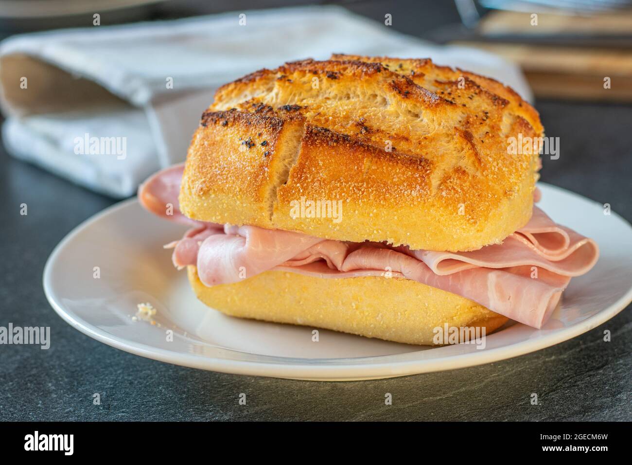 Sandwich au poivre allemand rustique et traditionnel et pain salé recouvert de fines tranches de jambon et servi sur une assiette Banque D'Images