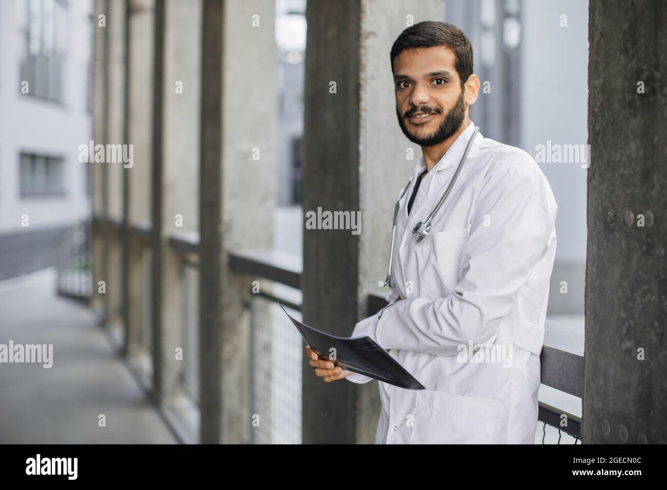 À la taille, portrait extérieur d'un jeune homme charmant et confiant,  médecin indien arabe, regardant la caméra, tenant le scanner à rayons X du  patient, posant près de la moderne h Photo