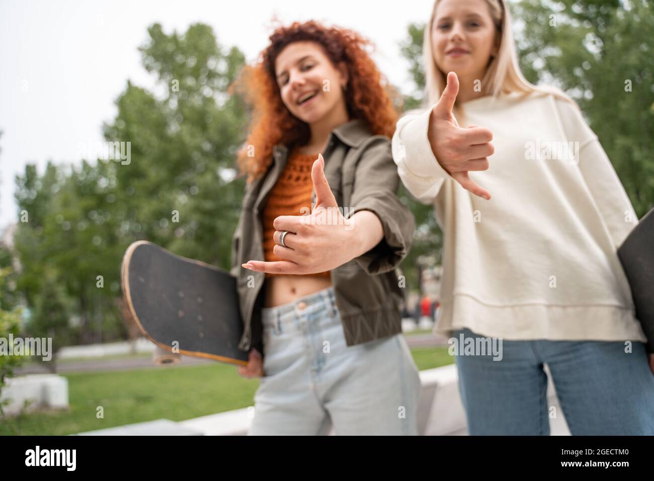 des patineurs flous montrant pendent des gestes lâches tout en souriant à l'appareil photo Banque D'Images