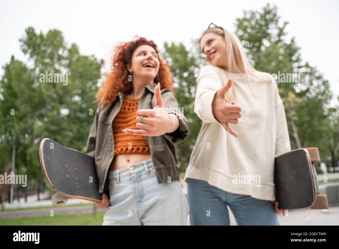 vue à angle bas des patineurs flous montrant le mouvement shaka tout en souriant l'un à l'autre Banque D'Images