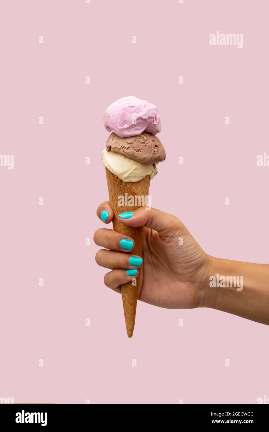 Main de femme tenant une crème glacée sur un fond rose Banque D'Images