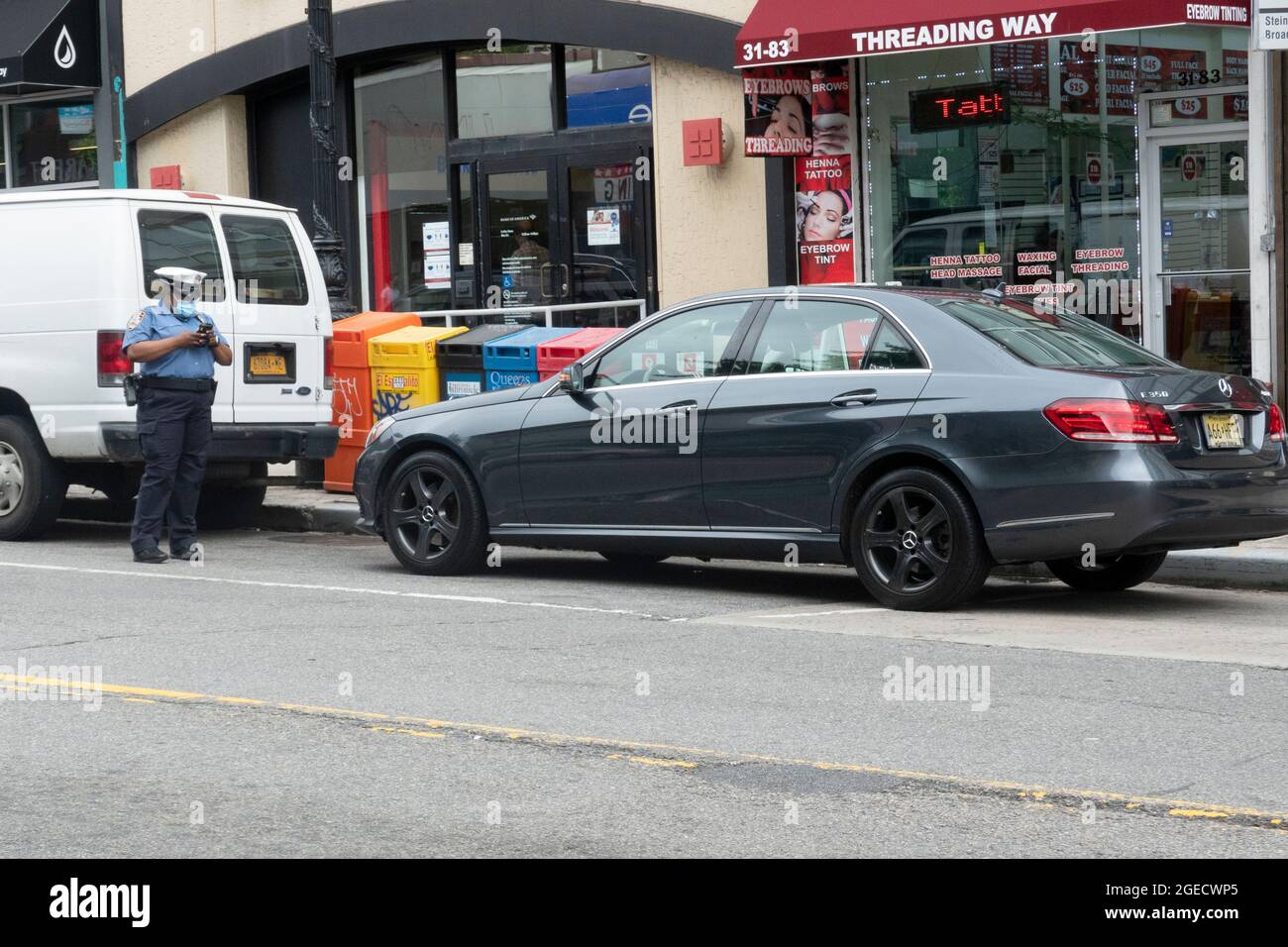 Un policier de la ville de New York prépare un billet de stationnement sur un appareil électronique. Sur Steinway Street à astoria, Queens, New York. Banque D'Images