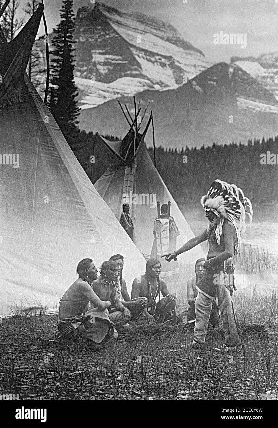 Rolan W Reed photo intitulée le Conseil - les anciens tribaux se rencontrent à l'extérieur de la tipi dans un paysage de montagne - 1912 Banque D'Images