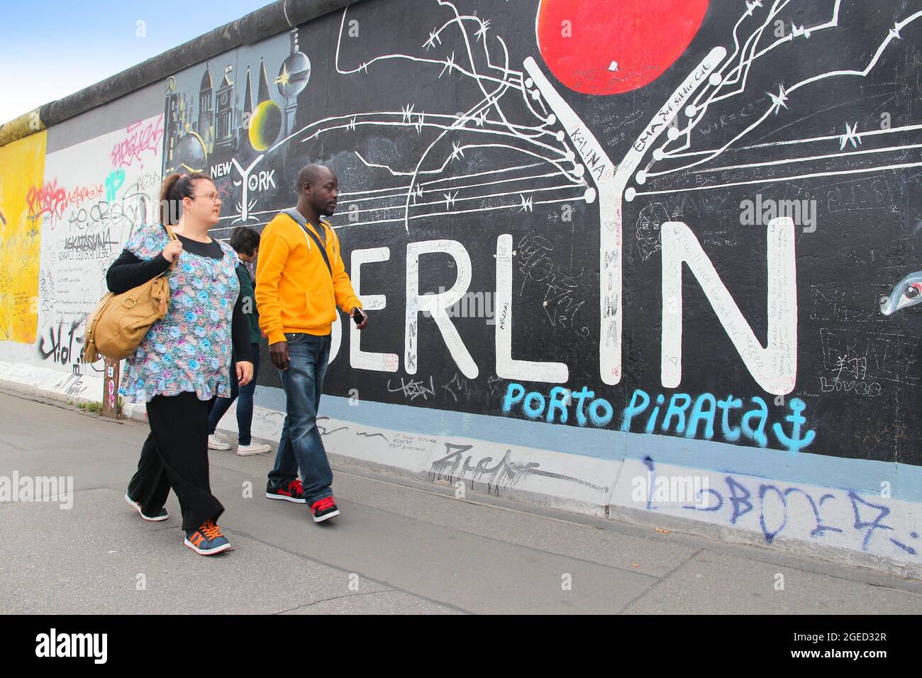 BERLIN, ALLEMAGNE - 26 AOÛT 2014 : les gens marchent sur un trottoir public le long du mur de Berlin (Berliner Mauer). La frontière emblématique du rideau de fer a divisé Berlin en Banque D'Images