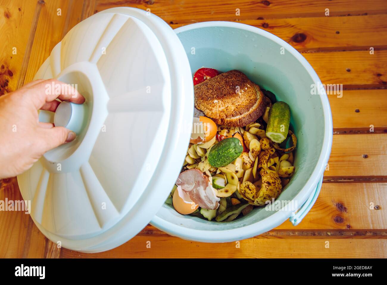 Les déchets d'aliments biologiques dans le seau à poubelle avec couvercle à la maison sur le sol à composter. Banque D'Images