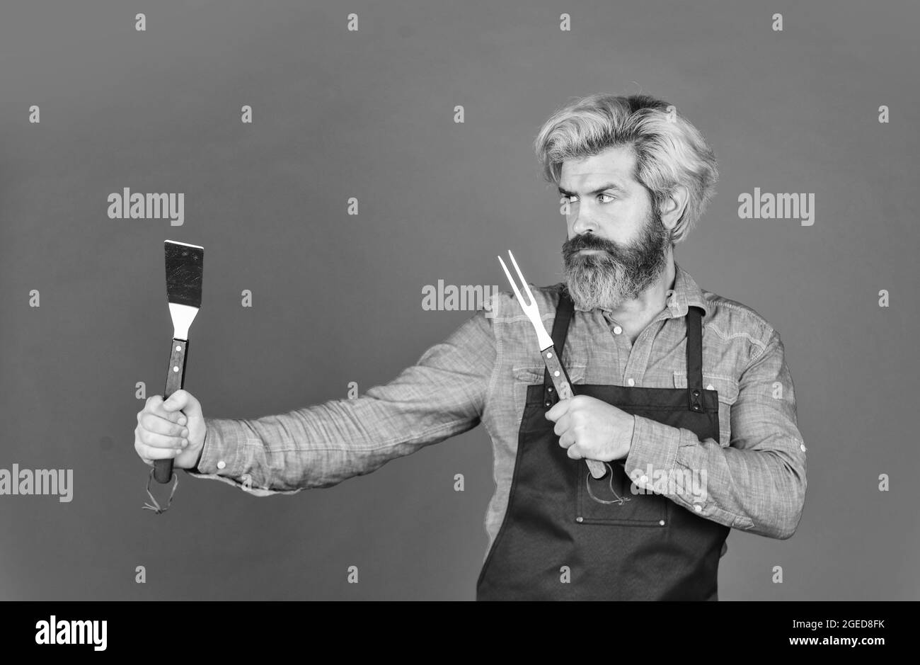 Outils pour rôtir la viande. Qui cuisinent mieux. Le défi ultime de la cuisine. Préparer le dîner pour la famille. Utiliser des ustensiles de cuisine et divers produits. Mature Banque D'Images