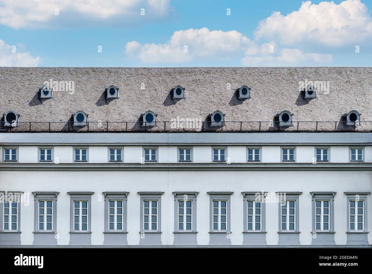 Le grand toit est couvert avec les carreaux plats de la vieille maison avec deux fenêtres rondes dans le grenier et les fenêtres normales sur le mur. Banque D'Images