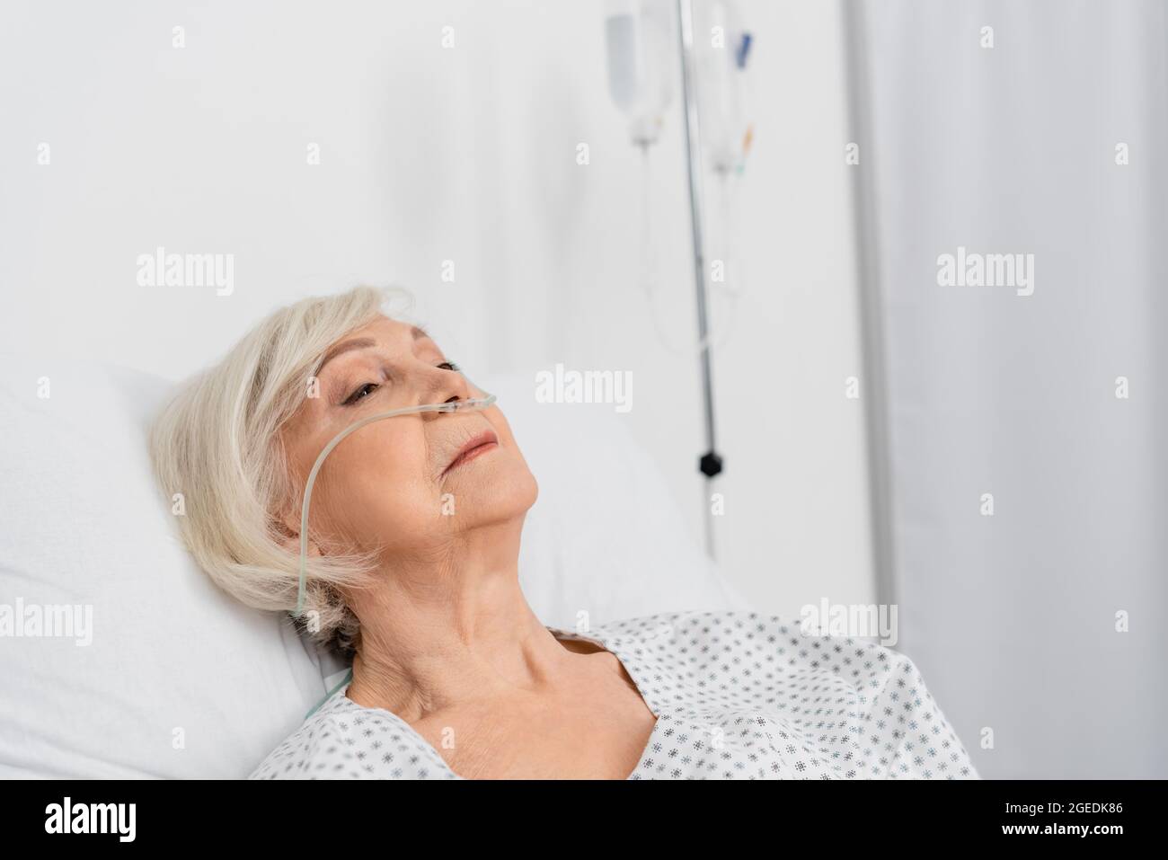 Patient âgé avec canule nasale couchée dans le service hospitalier Banque D'Images