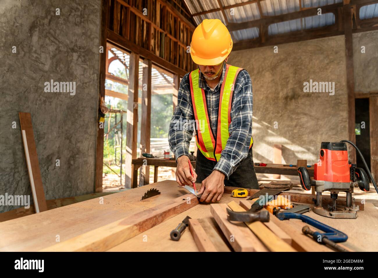 Un charpentier travaillant sur des machines à travailler le bois dans un atelier de menuiserie. Carpenter travaille sur le chantier de construction Banque D'Images