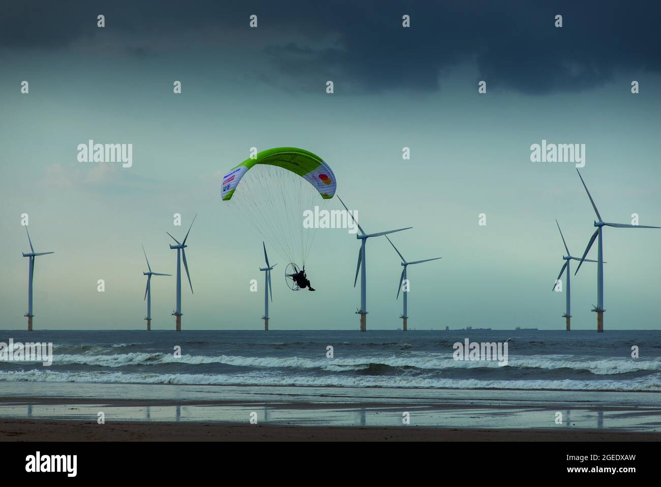 Sacha Dench le cygne humain volant son parapente électrique le long de Coatham Beach avec Teesside Windfarm au-delà. Redcar, Yorkshire du Nord, Angleterre Banque D'Images