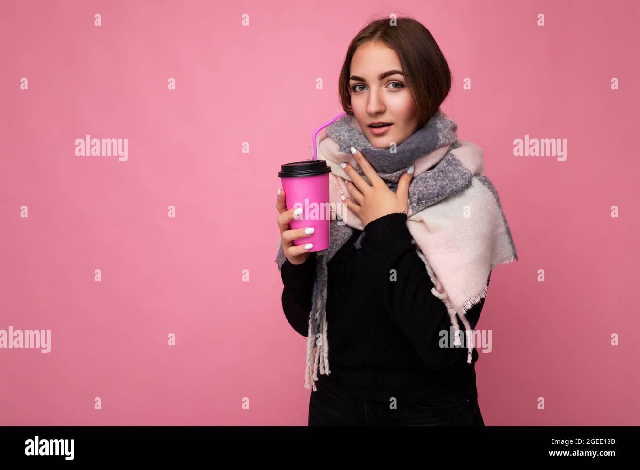 Belle malade jeune femme brune portant un chandail noir et une écharpe  chaude isolée sur fond rose tenant une tasse de café en papier pour mockup  boire Photo Stock - Alamy