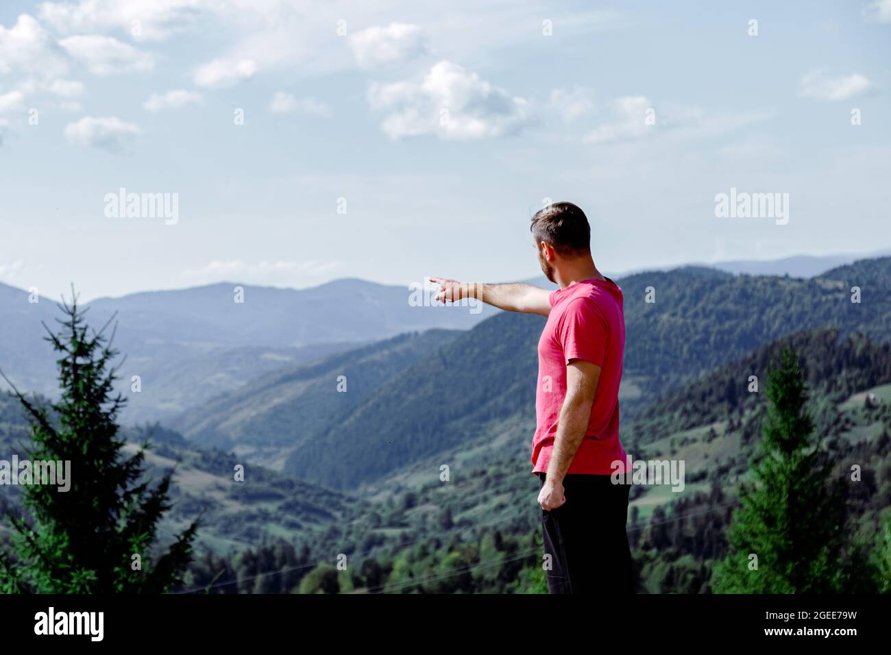 L'homme pointe sa main vers les montagnes. L'homme méconnaissable à l'arrière se tient devant le paysage de montagne et le ciel bleu Banque D'Images
