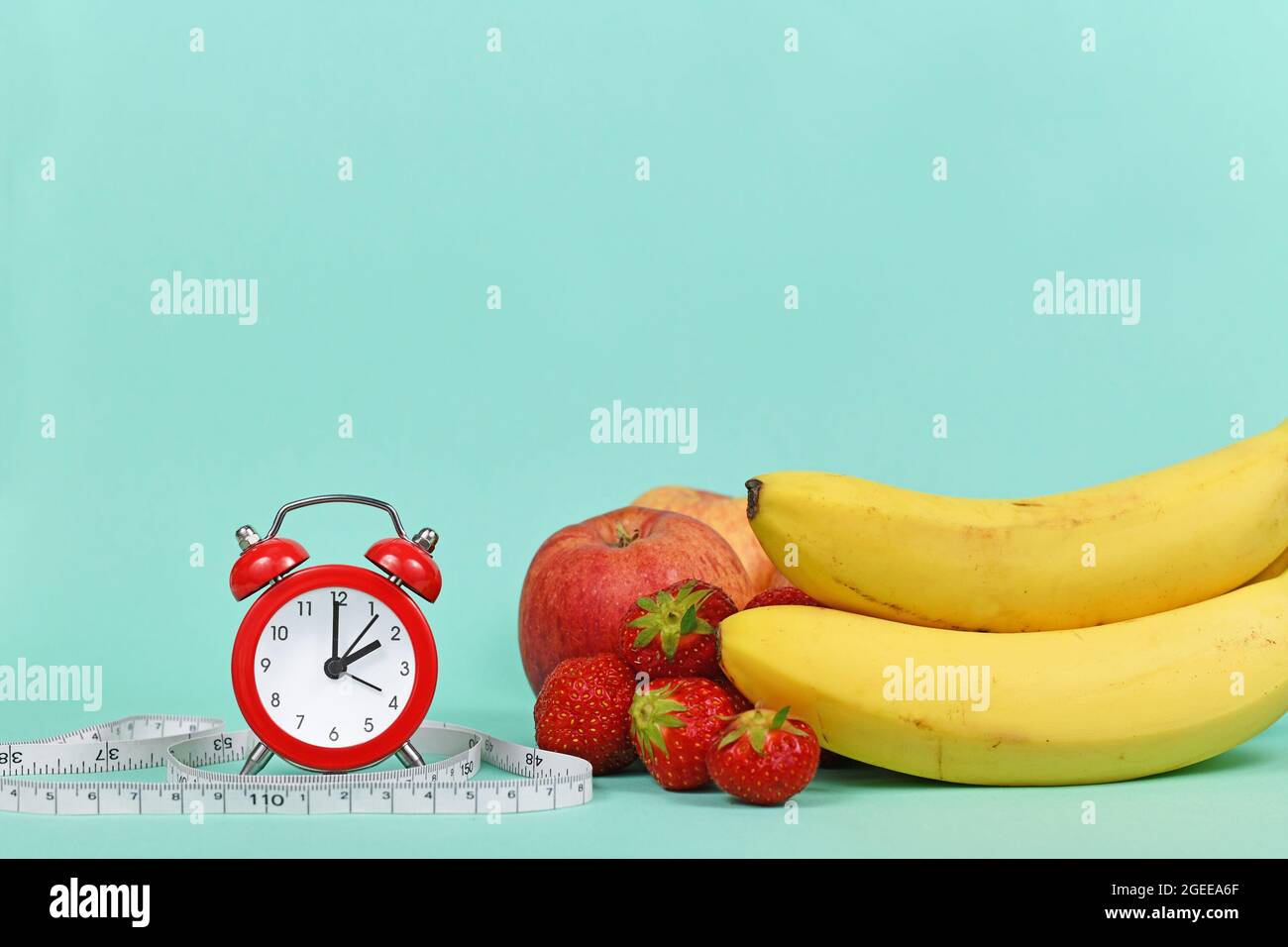 Concept de régime avec fruits, ruban de mesure et horloge sur fond bleu sarcelle avec espace de copie Banque D'Images