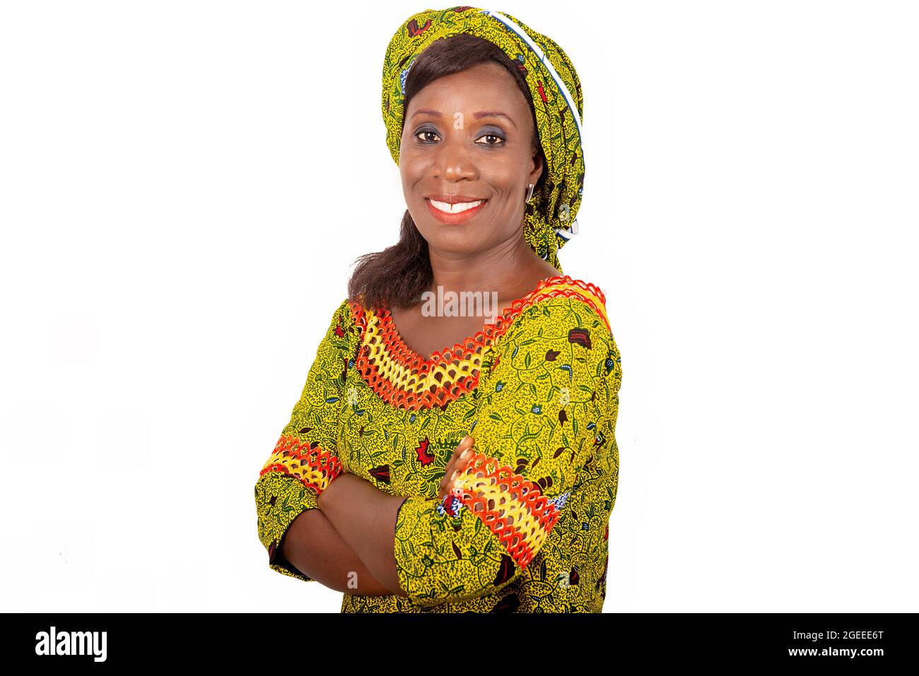 Belle femme adulte africaine vêtue de tissu vert est souriante en croisant ses bras Banque D'Images