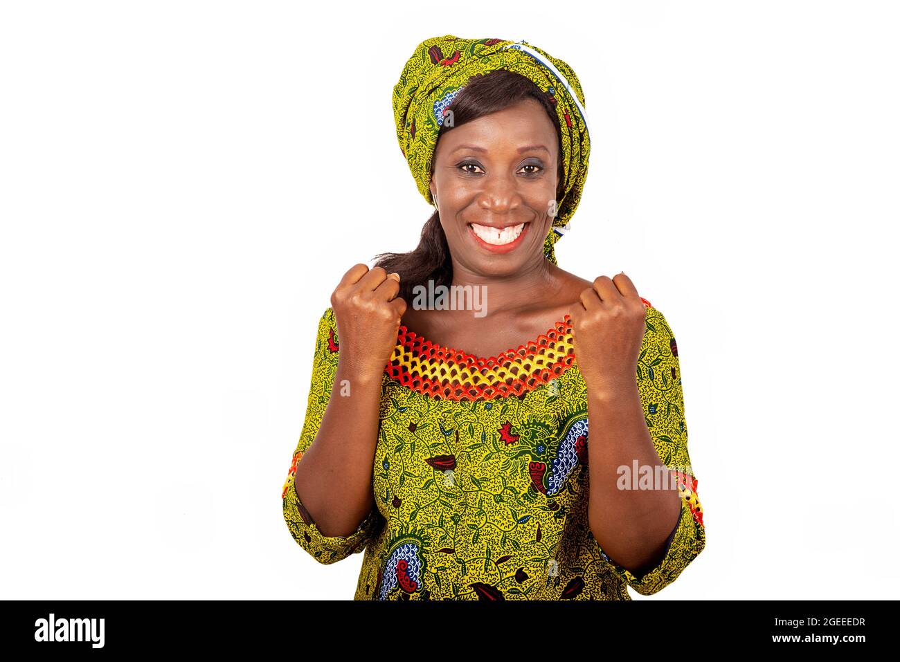 Belle femme adulte africaine vêtue de tissu vert montre sa victoire en levant les deux bras Banque D'Images