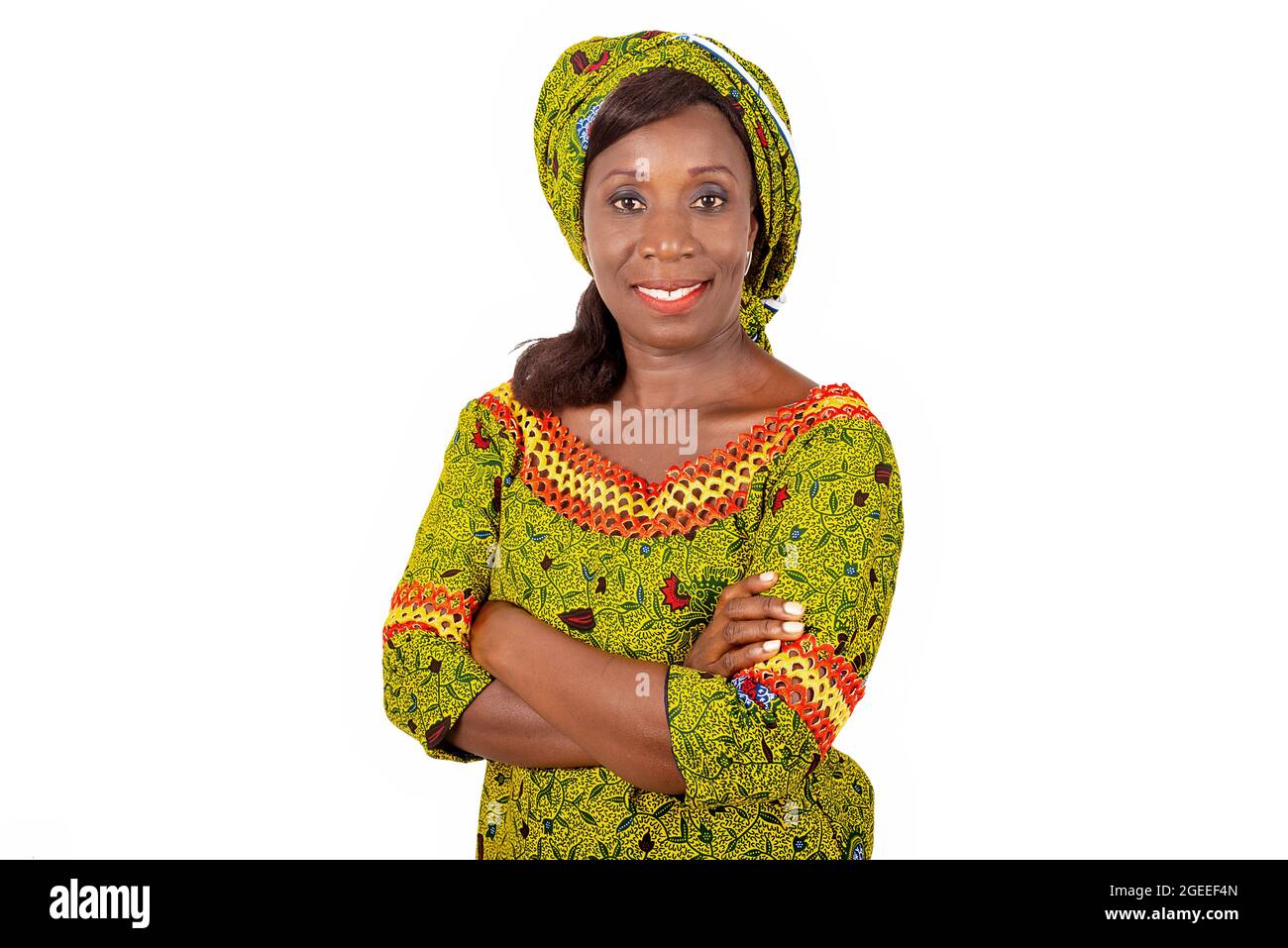 Belle femme adulte africaine vêtue de tissu vert est souriante en croisant ses bras Banque D'Images