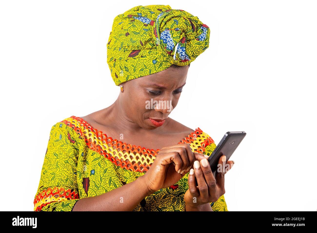 belle femme adulte africaine portant un chiffon et une écharpe verte manipule son téléphone portable noir Banque D'Images