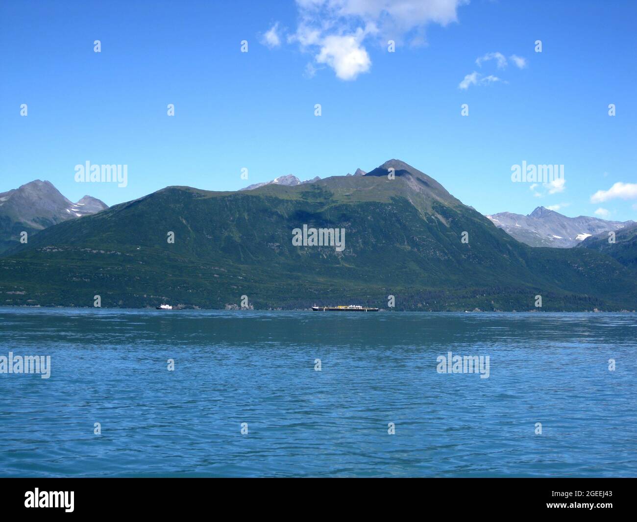 Deux bateaux partent vers le port sur la baie de Valdez, en Alaska. D'immenses chaînes de montagnes se profilent en arrière-plan. Banque D'Images