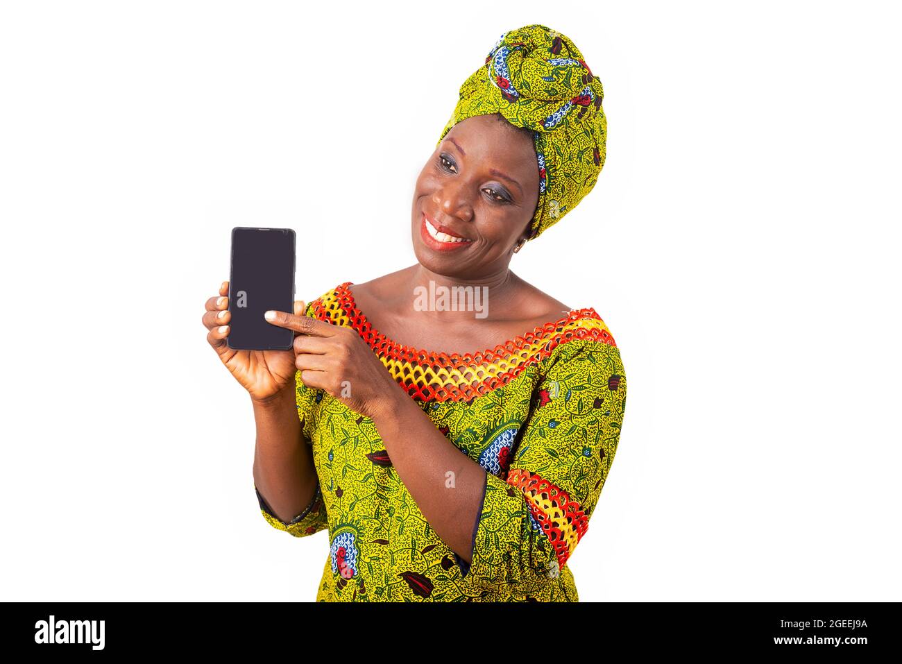 belle femme adulte africaine vêtue de tissu de longe et de foulard vert est heureuse de montrer son téléphone Banque D'Images