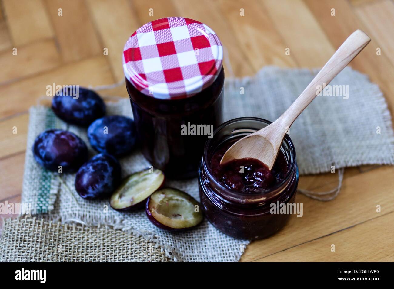 Cuillère rétro en bois dans un pot rempli de confiture de prunes sur un bureau. Gros plan, mise au point sélective et espace de copie Banque D'Images