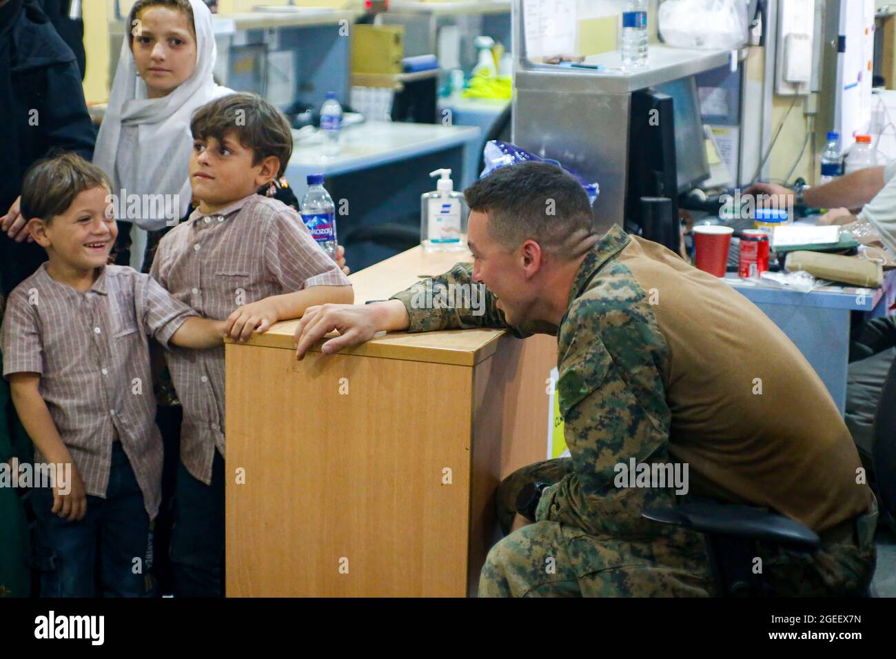 210818-M-JM820-1048 AÉROPORT INTERNATIONAL HAMID KARZAÏ (Afghanistan) (18 août 2021) – UNE marine américaine affectée à la 24e unité expéditionnaire maritime interagit avec des enfants lors d'une évacuation à l'aéroport international Hamid Karzaï (Afghanistan), le 18 août. Les membres du service des États-Unis aident le ministère d'État à procéder à un retrait ordonné du personnel désigné en Afghanistan. (É.-U. Photo du corps marin par lance Cpl. Nicholas Guevara) Banque D'Images