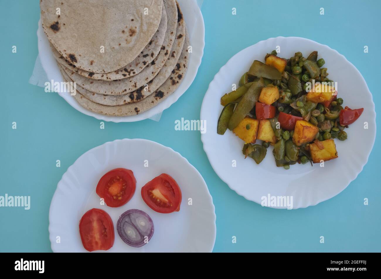 Cuisine indienne - légumes, rôtis et salades Matar paneer sur une assiette blanche avec fond bleu clair Banque D'Images