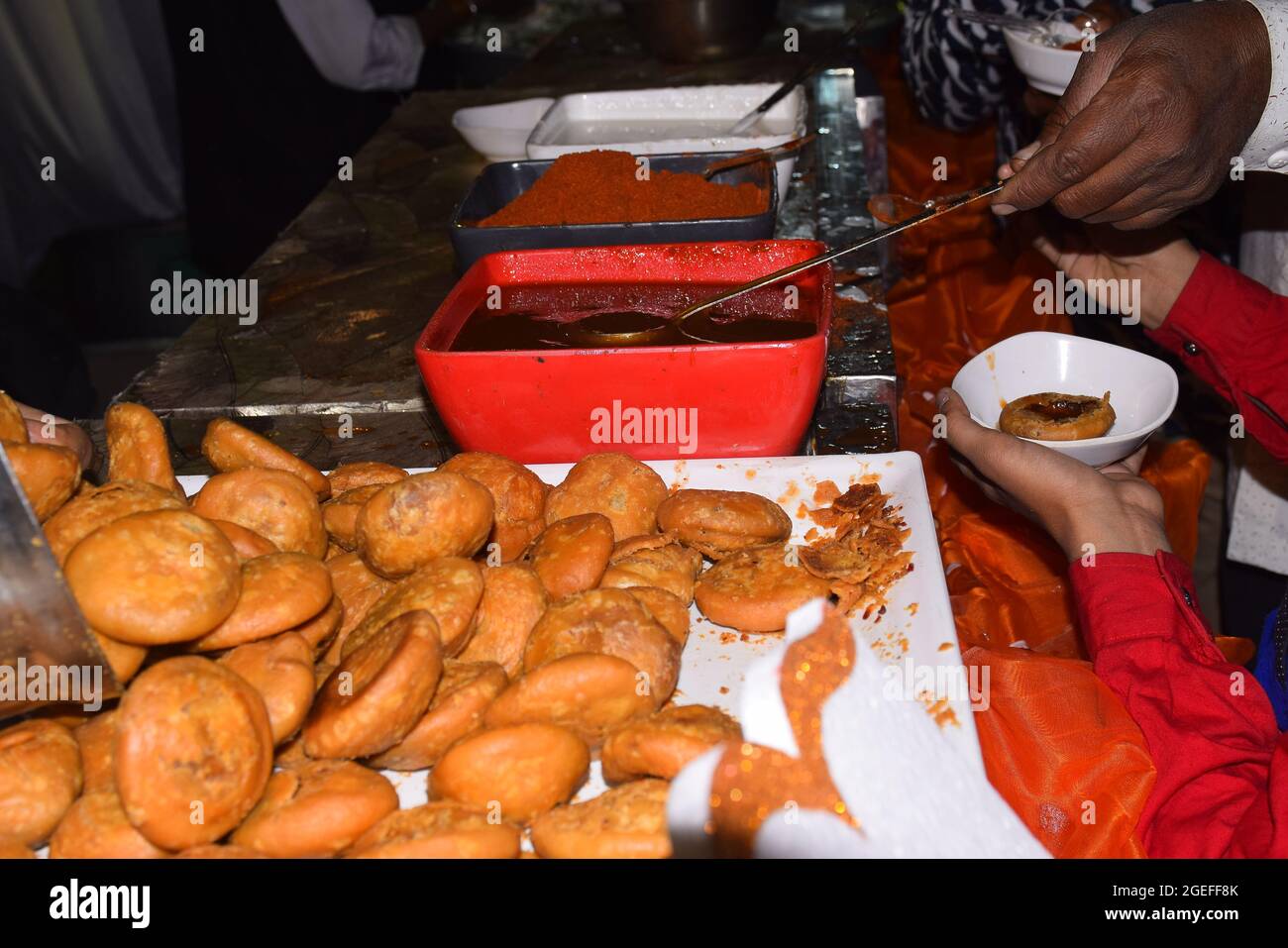 Main de l'Indien portant chutney à Kachori dans son assiette par une cuillère d'un grand pot Banque D'Images