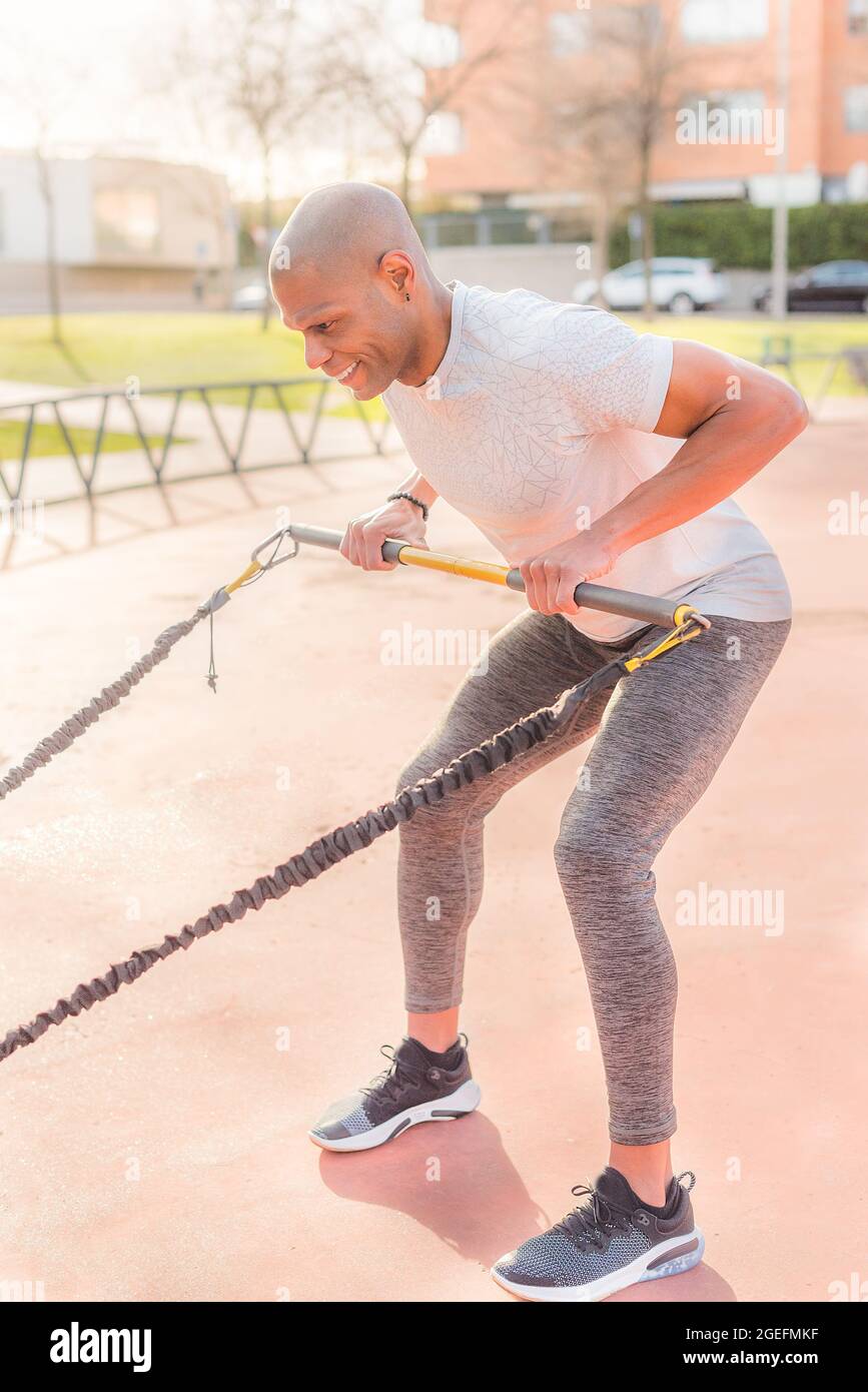 Atlhetic latin sportif s'entraîner avec une sangle de fitness dans le parc Banque D'Images