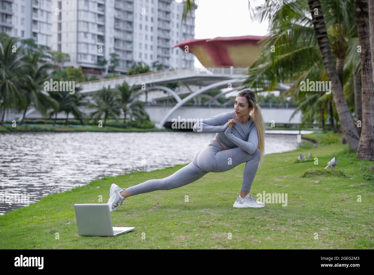 Exercice de yoga - femme faisant du yoga poser la méditation dans le parc public. Sport concept sain. Vêtements de sport gris Banque D'Images