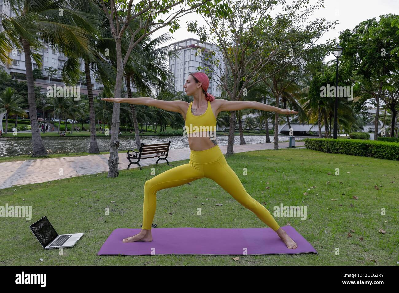 Jolie jeune femme faisant du yoga dans le parc. Vêtements de sport jaunes. Un mode de vie sain. Quarantaine. Photo de haute qualité Banque D'Images