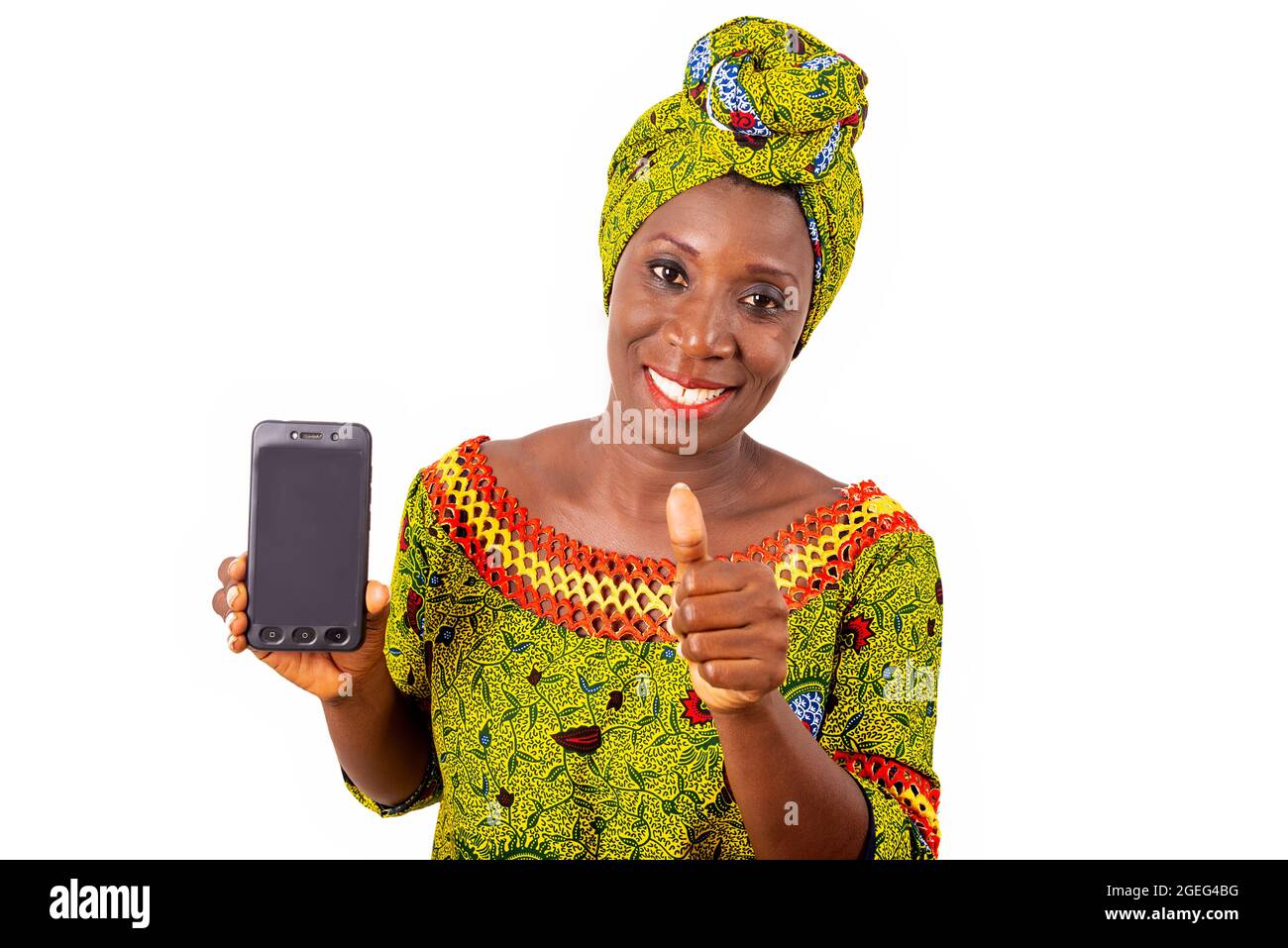 belle femme adulte africaine vêtue de tissu de longe et de foulard vert est heureux de montrer le pouce vers le haut avec son téléphone Banque D'Images