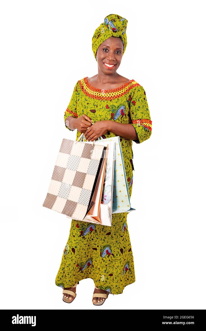 belle femme adulte africaine portant un chiffon et une écharpe verte est souriante et heureuse avec des sacs de shopping Banque D'Images