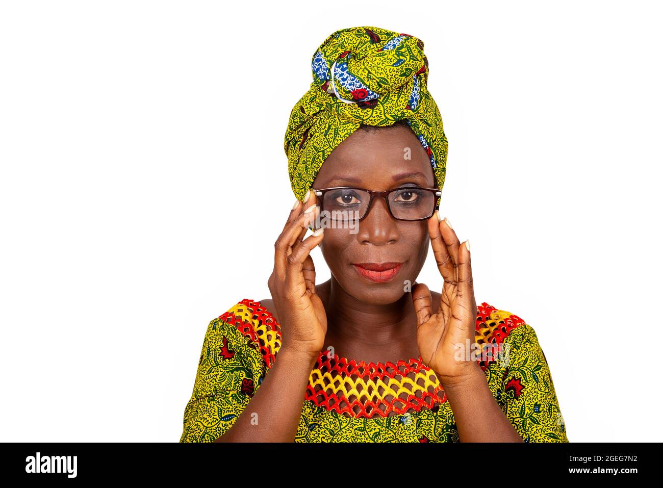 belle femme adulte africaine vêtue de tissu de longe et de foulard vert portant de belles lunettes aux yeux est souriant Banque D'Images